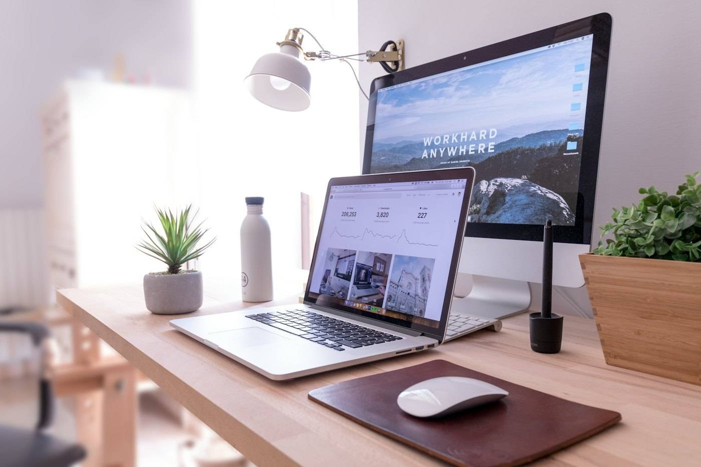 A designer's desk with a laptop showing a website layout